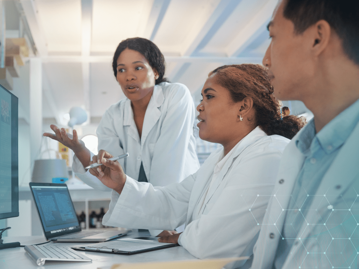 Three clinical researchers reviewing data together at a computer workstation in a laboratory.